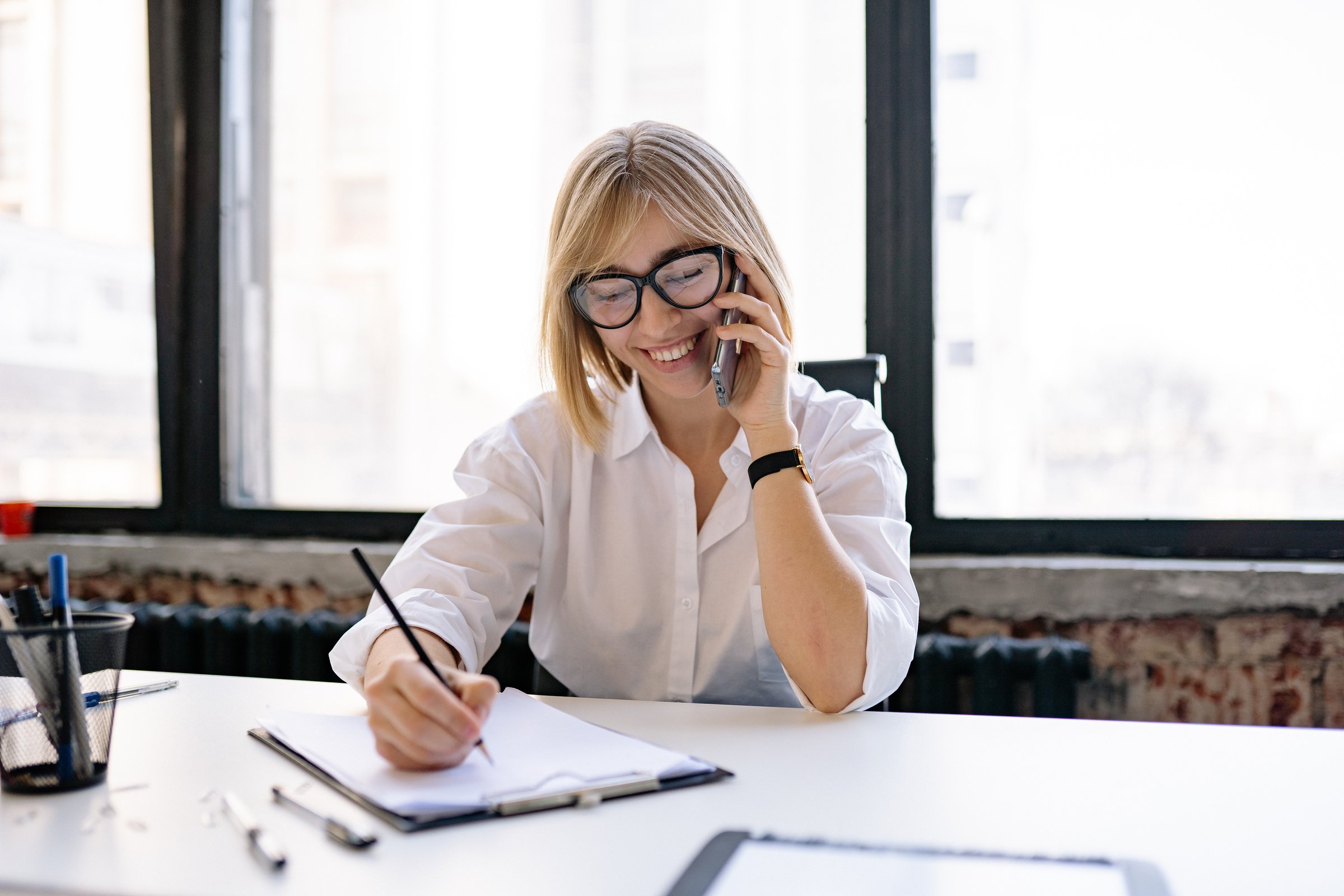 A Woman Taking Notes while in a Phone Call